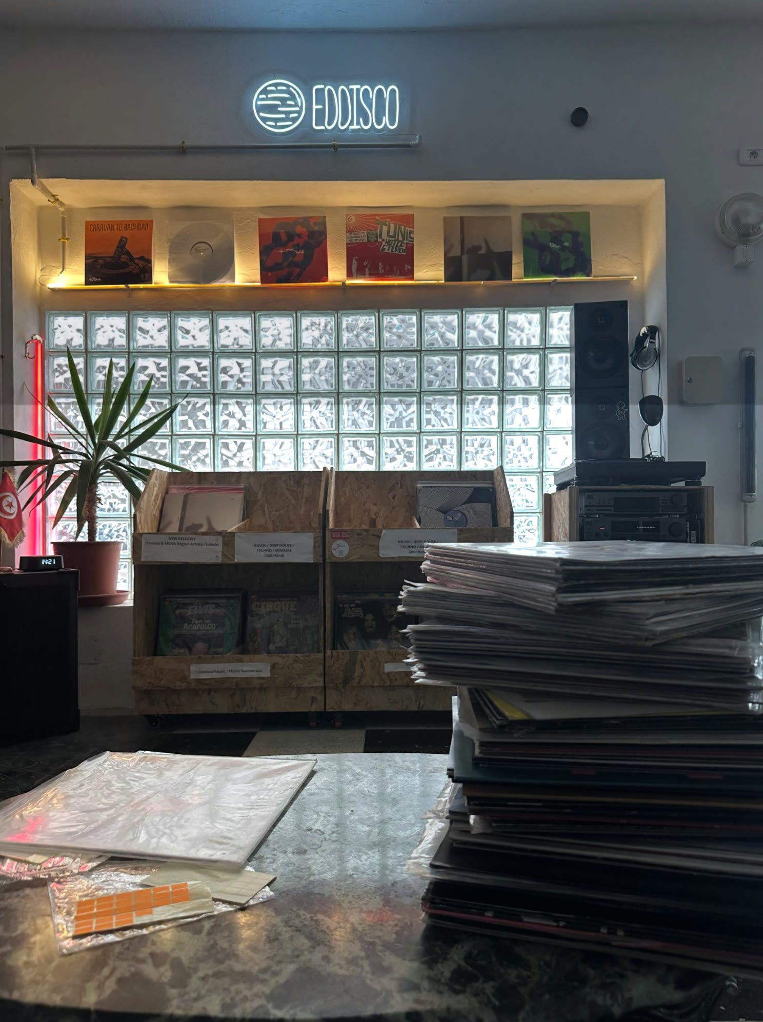 The Eddisco neon sign over lit record sleeves and the glass-block wall
